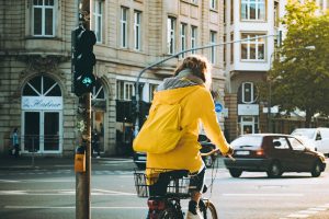Person in a yellow jacket cycling through the urban streets of Frankfurt, Germany.