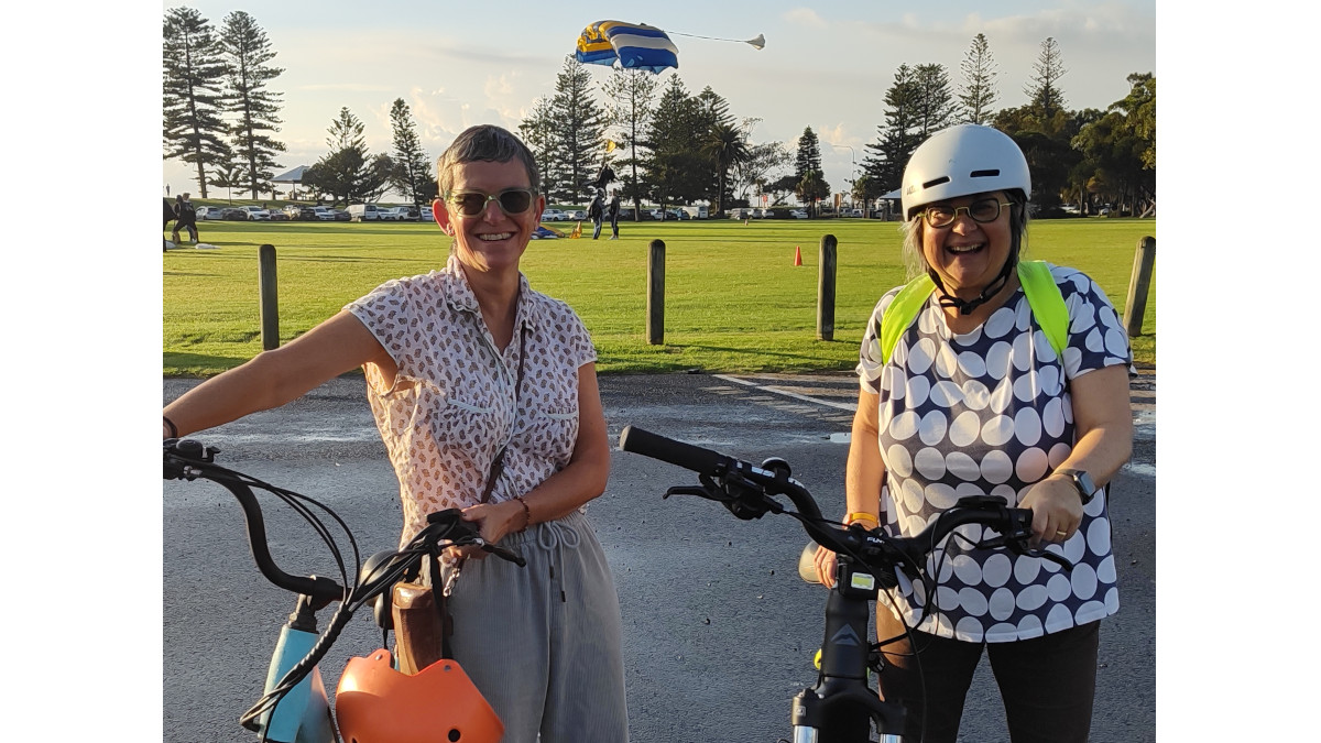 Two women smiling with ebikes before a ride at Wollongong foreshore